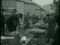 1938: SUDETENLAND: City street w/ people walking sidewalk. Police walking town lane w/ vendors FG. People shopping w/ outdoor fruit, vegetable vendors. Officer directing men into another door of public building. Mason working. VS Sudeten town. Instructional Video