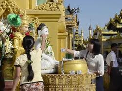 MS Shot of women pouring water on Buddha likeness at shrine in shwedagon pagoda / Yangon, Yangon Division, Myanmar Stock Footage