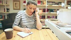 Caucasian young woman talking on the phone and writing notes. Stock Footage