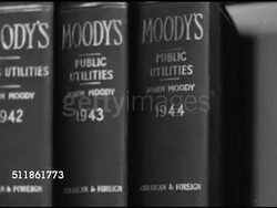 1946: NEW YORK STOCK EXCHANGE: MEMBER FIRM RESEARCH ROOM: WS People working at researching at desks, male at periodical rack, male at bookshelf. CU 'Moody's, Public Utilities' dated books, 1943, 44.  Male looking in book, placing back on shelf. Instructional Video