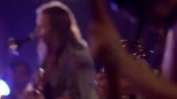 Young man shakes tambourine on stage with rock band in crowded music venue Stock Footage