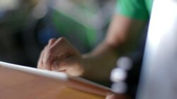 Bike shop employee scrolls up and clicks on tablet computer at sales counter Stock Footage