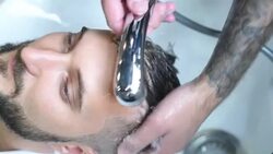 brutal hairdresser washes head of a bearded hipster Stock Footage