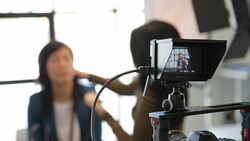 Makeup artist applying powder to face of businesswoman behind television camera Stock Footage