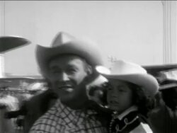 B/W 1950s PAN from Roy Rogers holding young girl to Dale Evans gesturing excitedly at airport Stock Footage