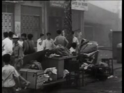 B/W PAN from group of Asians to smoke-filled street / 1960's / Saigon / NO SOUND Stock Footage