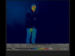 Thermographic imaging, cold man walks into frame from left, blows on hands to warm them, removes jacket Stock Footage