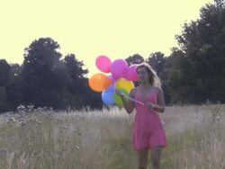 Woman walking through field with balloons; UK Stock Footage