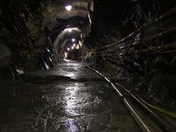 Lights dimly illuminate a tunnel with pipes running through it. Stock Footage