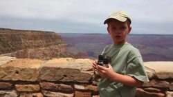 Young boy looks out at the Grand Canyon with binoculars and then holds the binoculars up to the camera lens Stock Footage