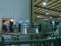 MS Filled plastic water bottles moving along conveyor belt, Wau, South Sudan Stock Footage