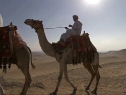 Wide Shot, crane tracking-left - Three men ride camels near the Great Pyramids in Egypt Stock Footage