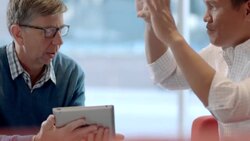 Businessman with tablet confers with corporate partner, partner pantomimes big picture Stock Footage