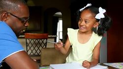 MS Smiling young girl in discussion with father while drawing in notebook at dining room table Stock Footage