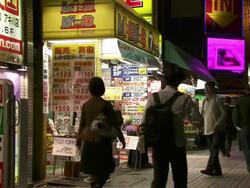 MS Shot of manga comic shop in Tokyo with pedestrians and traffic passing in front of it at night / Tokyo, Japan Stock Footage