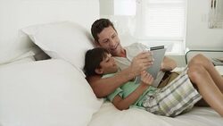 Father and son on bed using digital tablet Stock Footage
