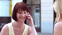 Woman talking on the phone while drinking coffee with friend Stock Footage