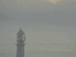 MS View of Lighthouse and ocean at sunset sunrise with lighthouse light turning round Stock Footage