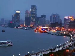 Time lapse high angle long shot view over the Bund promenade of skyline/ barges docking in river/ dusk to night/ Shanghai Stock Footage