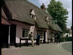 Men drinking outside Dog and Duck pub, policeman with bike walks past, Cambridge, England, UK 1960 Stock Footage