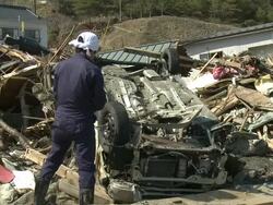 Man salvages tyres off his van which he just found in Kesennuma City, a traditional fishing town in N E Japan filmed on 1 April 2011, 3 weeks after a tsunami which was caused by magnitude 9 Tohoku earthquake off north east Japan / AUDIO Stock Footage