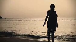 Young woman walking on sea shore during sunset Stock Footage
