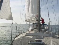 WS Pensioner ties down sail on his sailboat in sun on calm day / Wismar, Mecklenburg-Vorpommern, Germany Stock Footage
