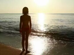 Little girl looking at sea sunrise Stock Footage