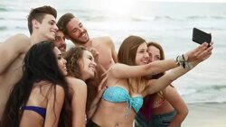 Group of friends taking selfies on the beach Stock Footage