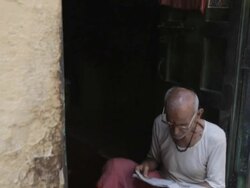 MS TD Man sitting in doorway reading newspaper / India Stock Footage