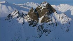 Snow clings to the sides of rugged rock formations atop mountains in the Yukon. Stock Footage