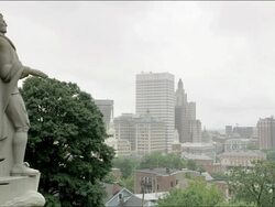 Statue of Roger Williams, founder of Rhode Island, at Prospect Terrace Park in Providence. Medium shot from the side of statue with the Providence city skyline in distance. No camera movement. Stock Footage