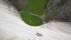 Female rock climber ascends artificial holds on concrete dam Stock Footage