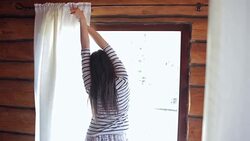 Young brown woman waking up from bed, pulling the curtain and stretching her arms. Stock Footage