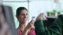 Girl takes smartphone photo of boy posing with sweater in trendy clothing shop Stock Footage