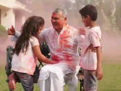Senior man playing holi festival with his grandchildren in a lawn  Stock Footage