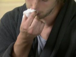 Young man sneezing and holding packet of tablets Stock Footage