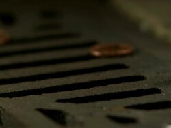 Money Down the Drain - High speed English coin, 10p, with British Lions design, falling on and rolling in to road drain, low angle 6 BCU Stock Footage