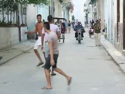 Shot of Teens playing handball Havana side street and Motorcycle, Pedicab moving on street Stock Footage