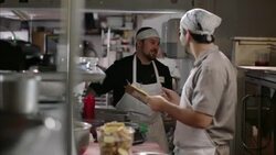 Head chef gives directions in kitchen as restaurant cook takes notes Stock Footage