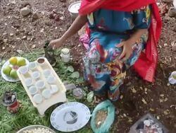 Ethiopian woman putting coffee pot over fire Stock Footage