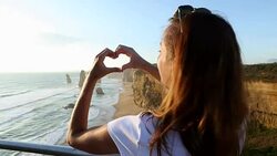Woman makes heart shape finger frame to Twelves Apostles-Australia Stock Footage