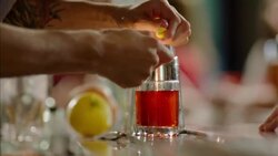 Skilled bartender sets lemon peel on fire, rubs around rim of glass, and serves cocktail Stock Footage