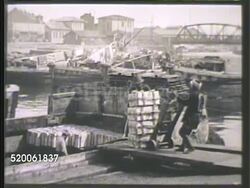 1942: TOKYO, JAPAN: HARBOR: * VS Japanese dock workers loading supplies, crates, on dock. WS 'Mitsubishi Warehouse' on pier, fisherman on boat lower FG. WS Ships in harbor. Instructional Video