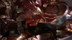 A scoop grabs a pile of bottle shaped Gummy candies filled with a liquid. Stock Footage