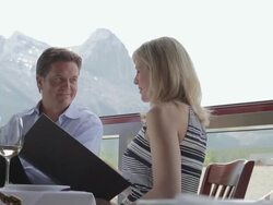 Couple discussing menu on patio overlooking mountains Stock Footage