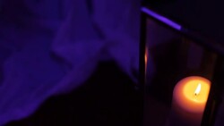 Lit candles on table in purple light Stock Footage