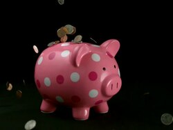 CU SLO MO Coins being dropped onto pink polka dot piggy bank / Studio, New Jersey, USA Stock Footage