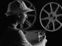 Young woman watching movie in old fashioned style film projector Stock Footage
