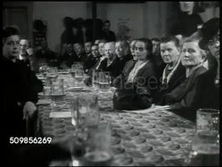 1946: NEW PARTY MEETING: People reading CDU (Christian Democratic Union) posted handbill. German people sitting inside hall listening to CDU speaker at podium, VS people sitting at long tables, drinking beer, listening. Speaker talking (no SOT). Instructional Video